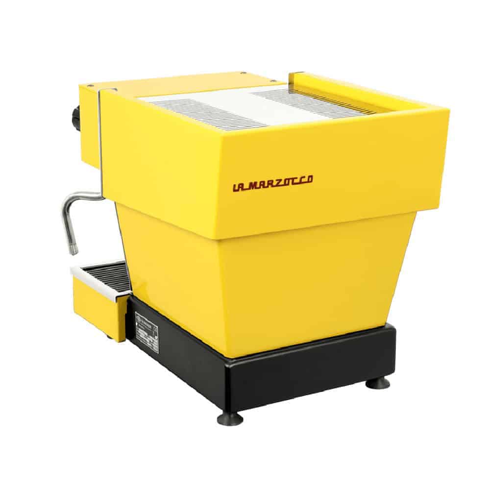 מכונת אספרסו צהובה מדגם La Marzocco, המצוידת במוט אדים ומגש טפטוף, הנראית מזווית המציגה את הצד והחלק האחורי — מושלמת להכנת מנות אספרסו עשירות בארומה ולהנאה מכוס קפה מושלמת. | אספרסימו