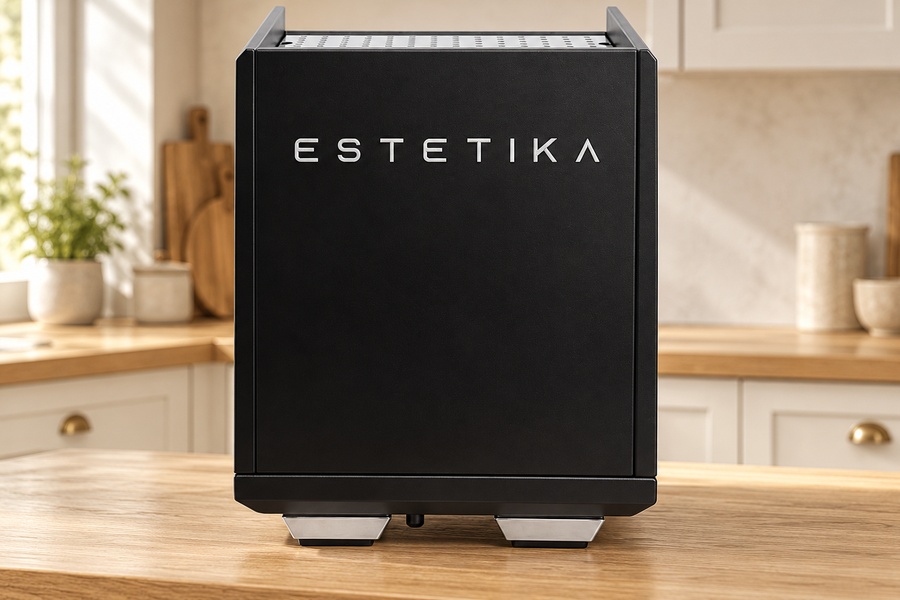 מכונת אספרסו ECM Technika V Profi PID בצבע שחור, שעליה מודפסת המילה “ESTETIKA” בחזית, מונחת על משטח מטבח מעץ. | אספרסימו