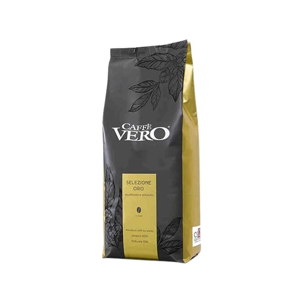 שקית בצבעי שחור וזהב של פולי קפה Caffe Vero GOLD במשקל 1 ק"ג עומדת זקופה. בחזית השקית מופיעים לוגו המותג, סמל של כוס קפה וטקסט תיאורי. האריזה, המיועדת לשימוש במכונת קפה, מעוטרת במוטיבים של עלים על רקע לבן המרמז על הארומה העשירה של המוצר. | אספרסימו