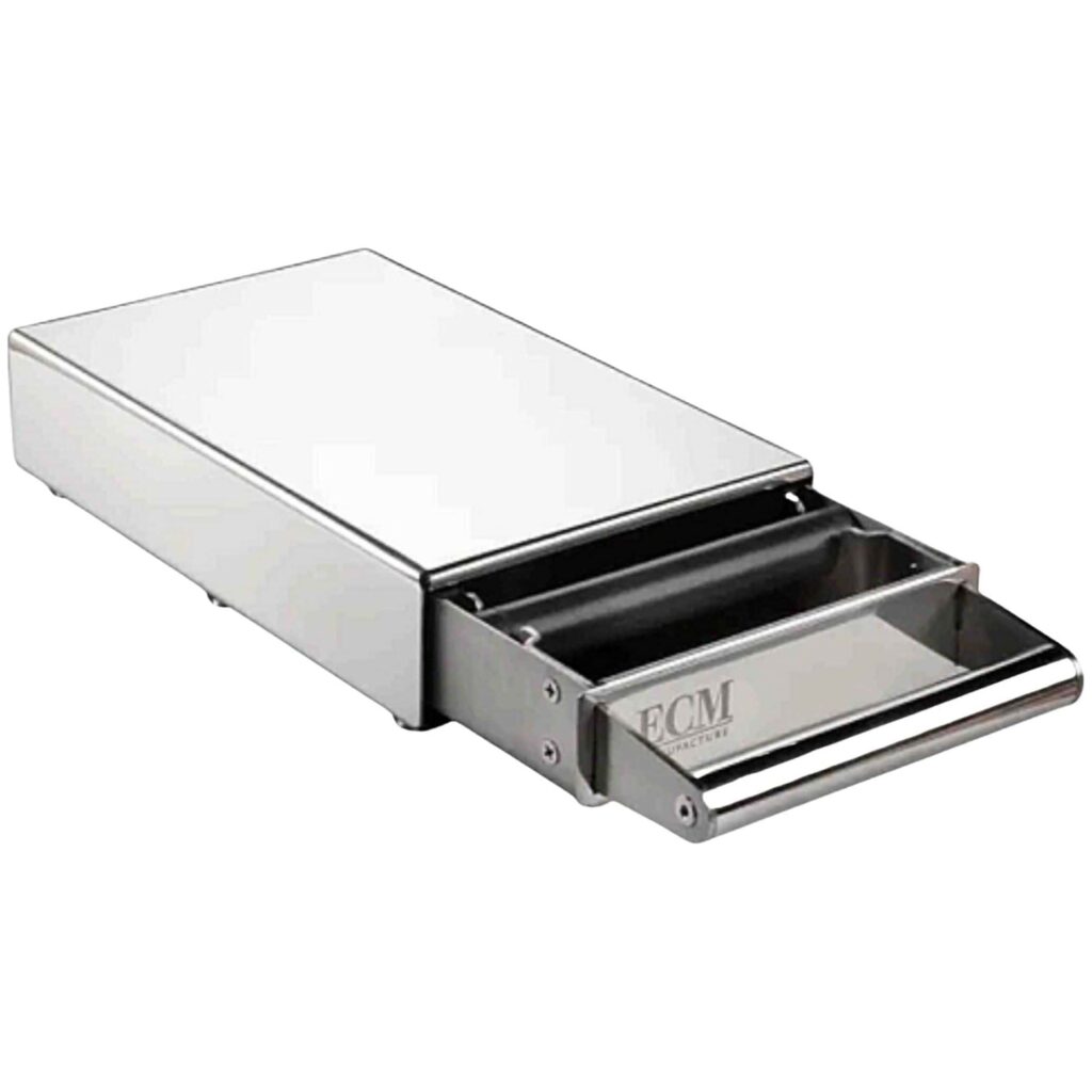 הכירו את מגירת הנוקבוקס לקפה M - ECM Knock Box, המיוצרת מפלדת אל-חלד ומיועדת למכונת קפה. המגירה, המוצגת כאן כשהיא פתוחה חלקית, כוללת ידית נוחה ותא ייעודי לפינוי קל של קפה טחון משומש — מה שהופך אותה לאביזר המושלם לשמירה על הארומה בדרך להכנת כוס קפה מושלמת. | אספרסימו