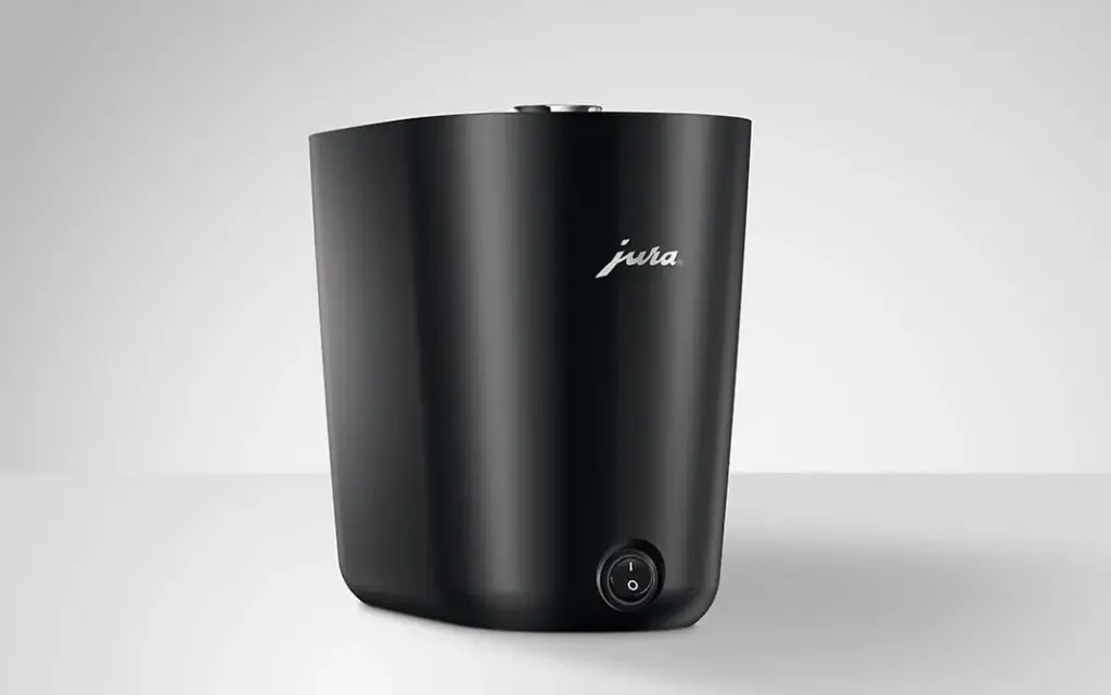 מכשיר Jura Cup Warmer S לבן ומודרני, עם כפתור הפעלה בחלקו הקדמי התחתון ולוגו Jura המופיע בחלקו העליון, המוצב על רקע פשוט ובהיר. | אספרסימו