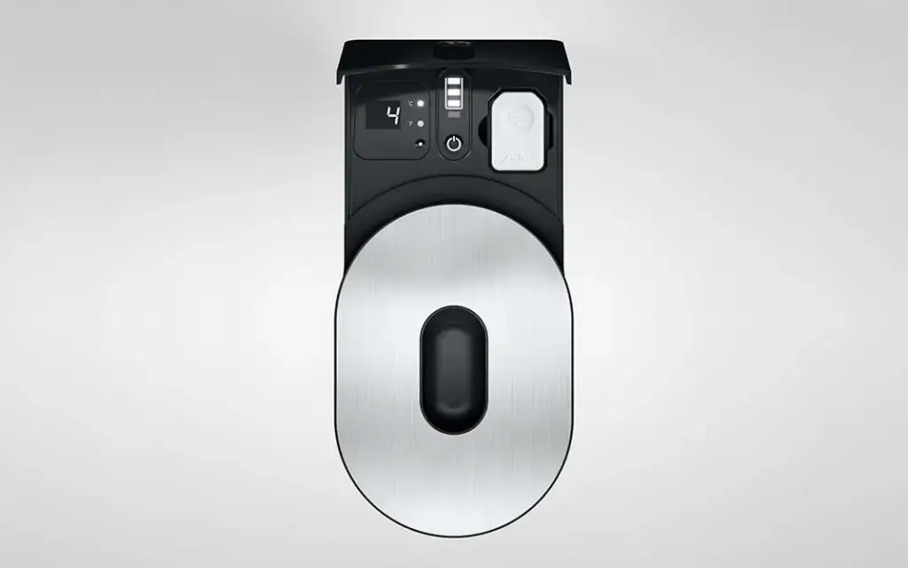 תצוגה מלמעלה של מקרר החלב Cool Control בנפח 0.6 ליטר בצבע שחור למכונות הקפה של JURA, המתאפיין בעיצוב מטאלי מודרני עם תצוגה דיגיטלית וכפתורים שונים בלוח הבקרה, על רקע אפור בהיר אחיד. | אספרסימו